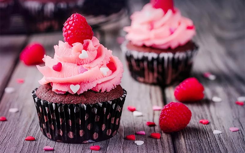 two chocolate cupcakes with pink icing and red hearts for Valentine's Day